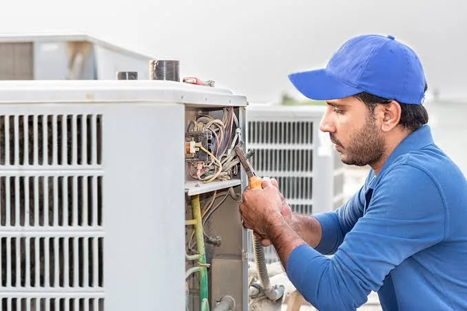 Representative image of an outdoor air conditioner being inspected for repair